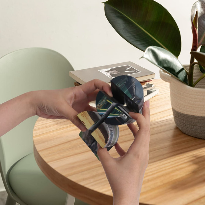 A hands-on demonstration of a 3D Flips Cylinder Magic Cube with green and black sections, resting on a wooden table.