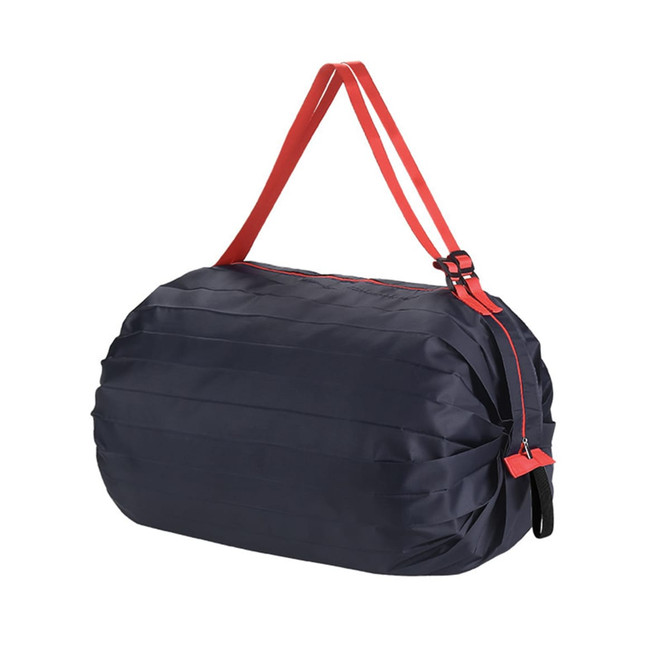 A foldable shopping shoulder bag in navy blue with red straps, featuring a zippered closure and a logo.