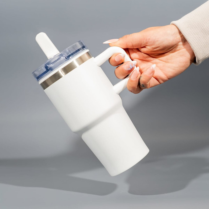 A drink bottle with a white double wall design and a clear lid, held by a hand against a grey background.