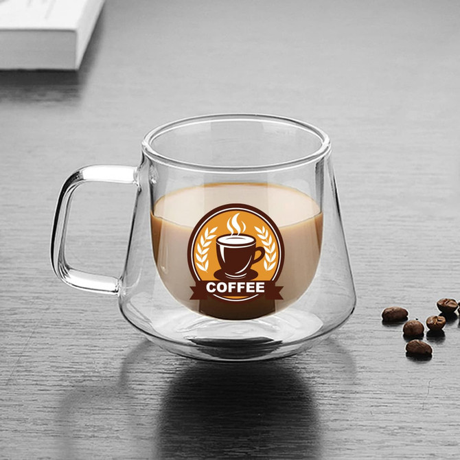 A transparent double wall glass mug with a handle, containing coffee and surrounded by coffee beans.