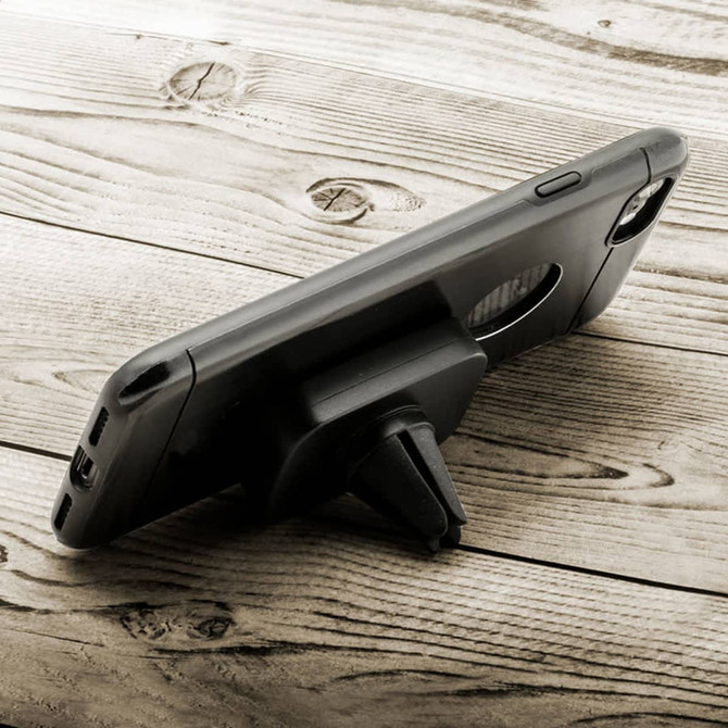 A black rectangular phone holder with a stand, placed on a wooden surface. It features a logo.