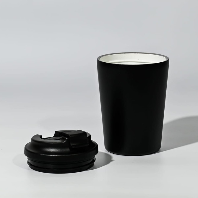A black travel cup with a removable lid, featuring a sleek design and a contrasting inner colour.