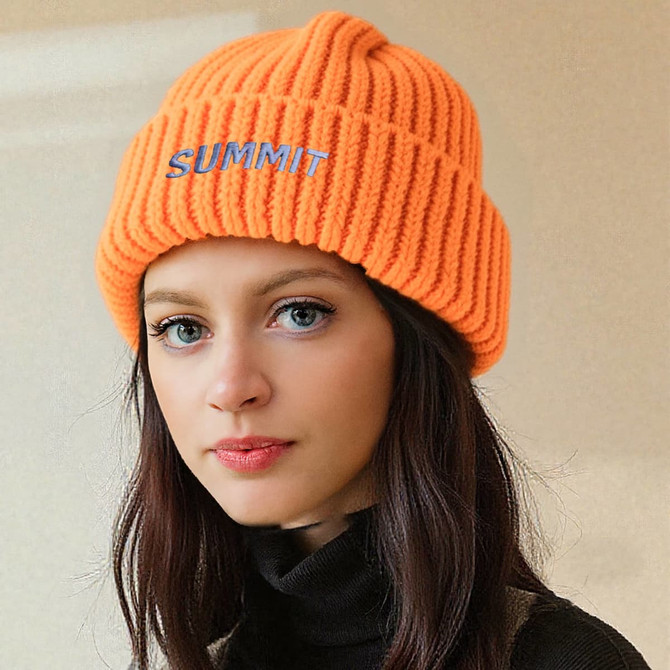 A twisted cable cuffed beanie in bright orange, featuring a logo on the front, worn by a model.