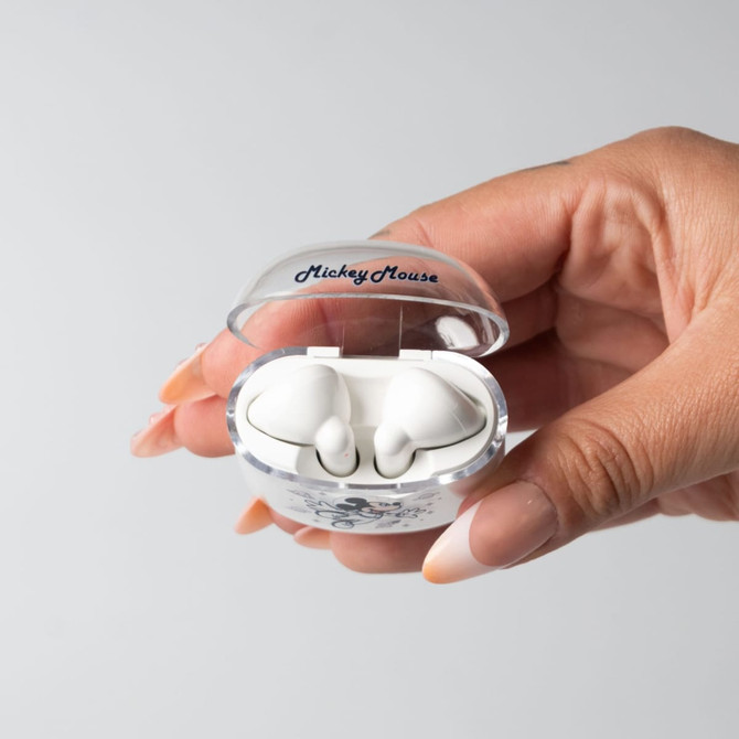 A hand holding a clear earphone case containing white earphones with a logo on top.