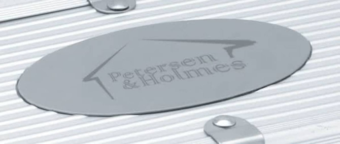 A silver metal plate with the brand name engraved, featuring a simple logo on a textured surface.