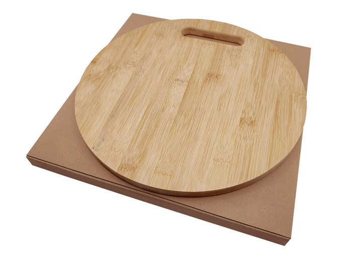 A round bamboo cheese board with a handle, resting on a brown kraft box.