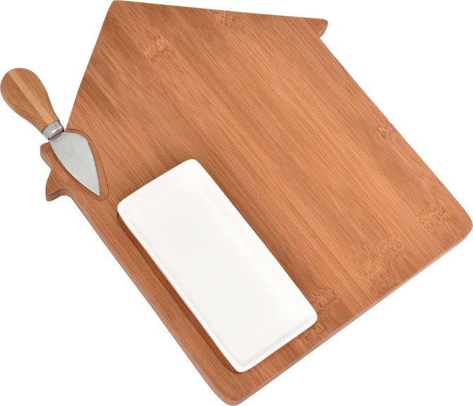 A bamboo cheese board shaped like a house, featuring a metal cheese knife and a small white serving dish.