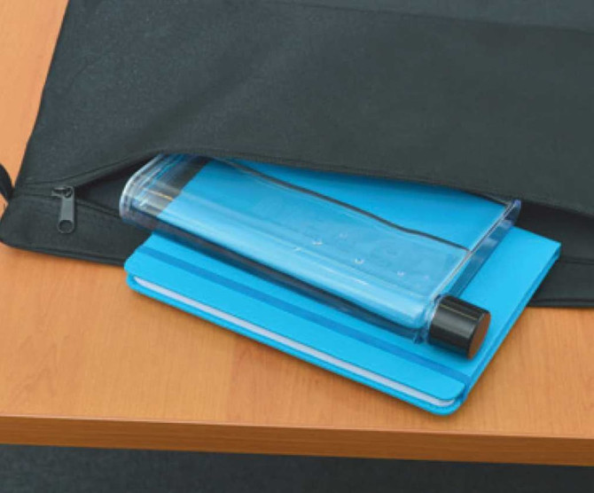 A drink bottle in a clear blue colour sits atop a blue notepad, inside a black bag on a wooden table.