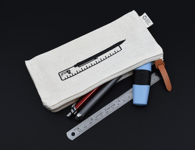A cream-coloured pencil case with a ruler graphic, containing pens, a highlighter, and a ruler, with a leather zipper pull.
