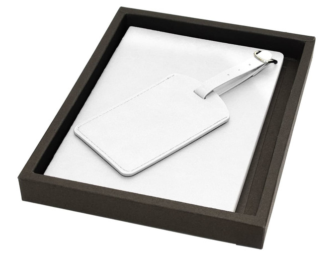 A white leather luggage tag and soft cover journal set in a black presentation box.