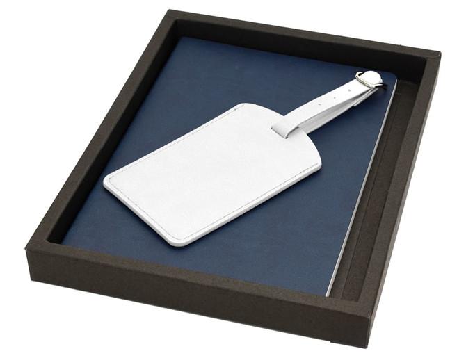 A navy blue travel journal set with a white luggage tag, presented in a black box.