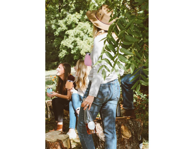 A group of people enjoying the outdoors, holding various drink tumblers, including a white and a colourful tumbler.
