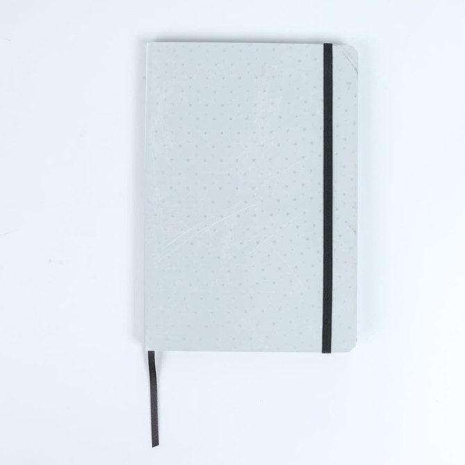 A grey notebook with a dotted design and a black elastic band, featuring a ribbon marker.