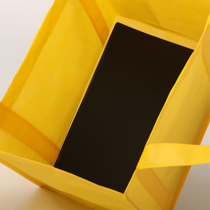 A yellow tote bag containing a black item, featuring sturdy handles and a simple design.