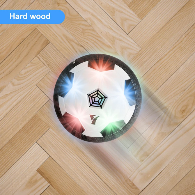 A hover soccer ball with a black and white design, featuring coloured lights, on a hardwood floor.