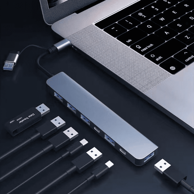 A silver 7-in-1 USB hub connected to a laptop, with multiple cables plugged into it.