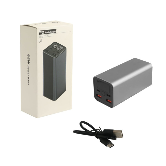 A sleek grey power bank beside its box, featuring two USB ports and a charging cable. It has branding on the packaging.