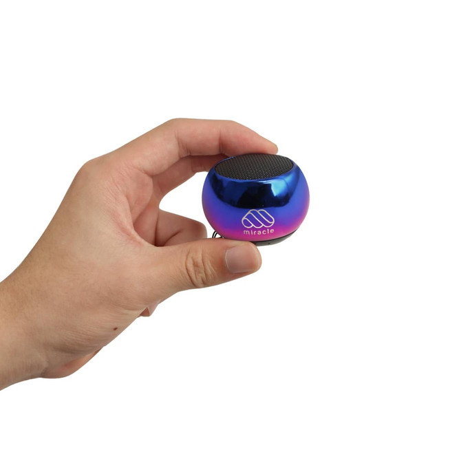 A hand holding a small, round, iridescent blue and purple Mini Bass Wireless Speaker with a logo.