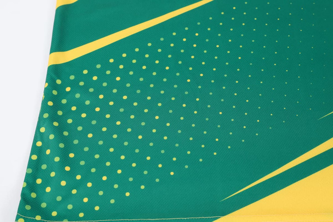 A green and yellow sublimated sports long sleeves shirt featuring a dotted design and angled stripes, with a logo present.