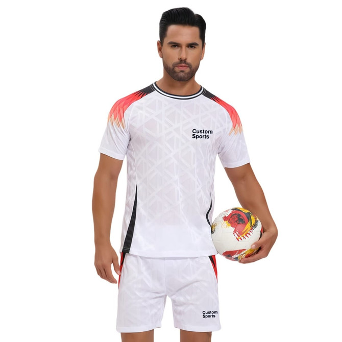 A man wearing a white crew neck tee shirt with red and black accents, holding a soccer ball. The shirt has a logo.