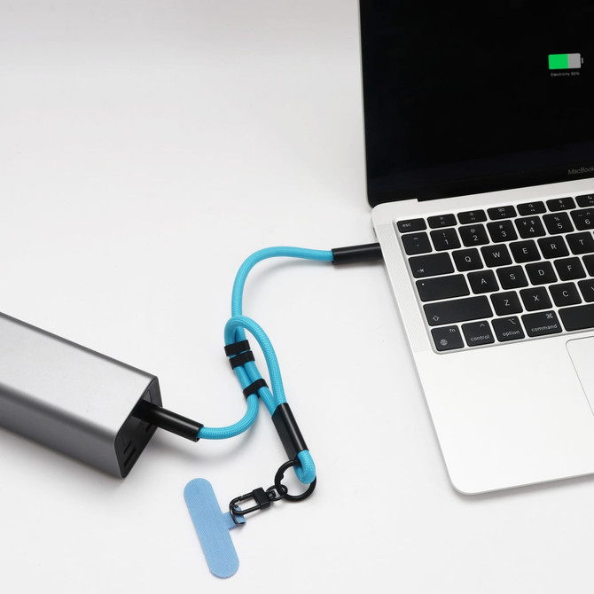 A silver charging power bank with a blue strap connected to a laptop. The image features a logo on the power bank.