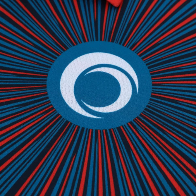 A blue and red polo shirt featuring a circular logo at the centre and radiating lines around it.