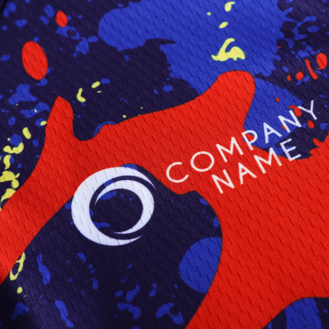 A close-up of a men's cycling jersey featuring a vibrant design with red, blue, and yellow splashes, and a logo.