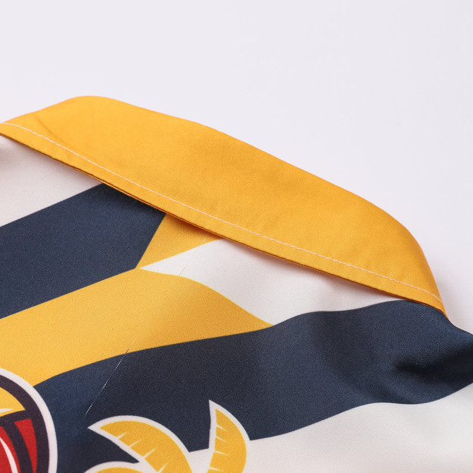 A close-up of a women's button-up shirt featuring a yellow collar and a colourful Hawaiian print.