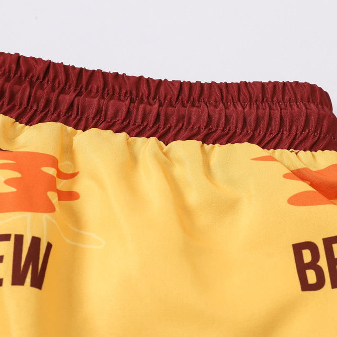 Men's polyester board shorts featuring a yellow body with maroon elastic waistband and a logo.