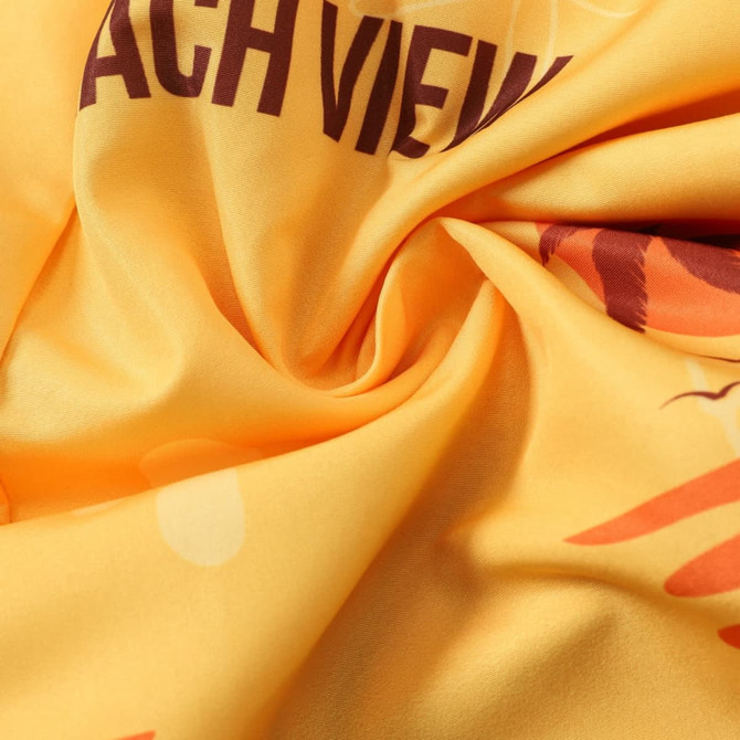 A close-up of yellow polyester fabric with a smooth texture and bold patterns, including a logo.