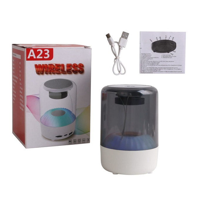 A portable Bluetooth speaker in white and grey, accompanied by a box, USB cable, and user instructions.