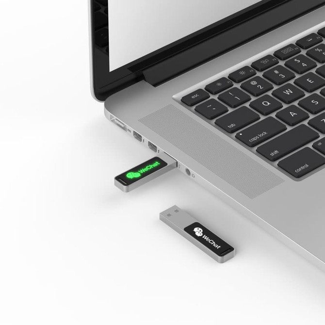 A USB flash drive in silver and black, partially inserted into a laptop's USB port, with branding visible.