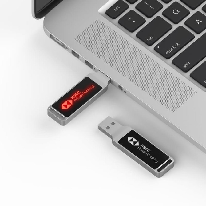A black and silver LED flash drive connected to a laptop, featuring a logo on the drive.