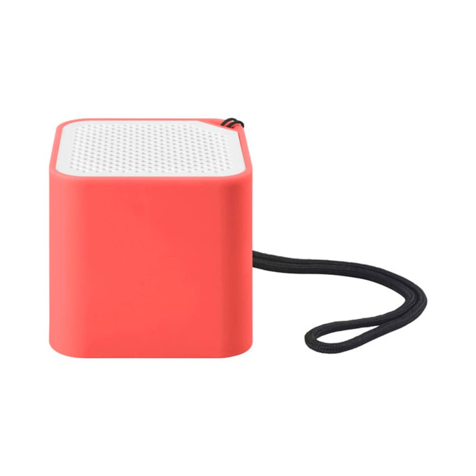 A compact square speaker in coral with a textured white top and a black strap attached.
