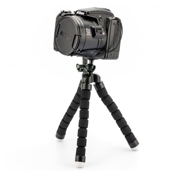 A black camera mounted on a flexible tripod with black foam grip legs and white rubber feet.