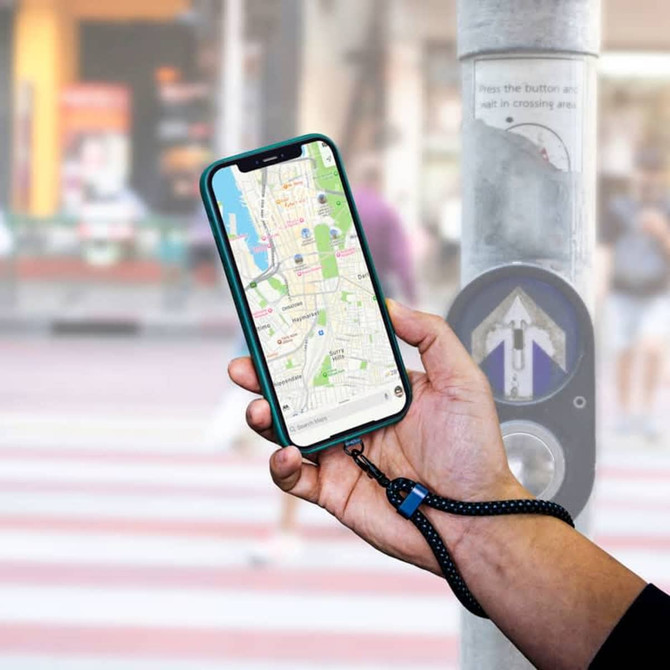 A hand holding a smartphone displaying a map, attached to a black eco-friendly wristband strap.