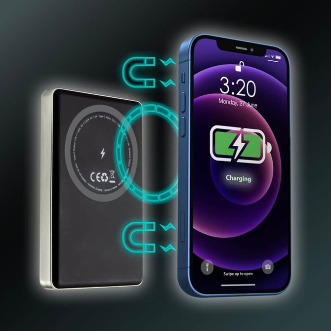 A black MagSafe wireless power bank beside a smartphone with a charging symbol on its screen.