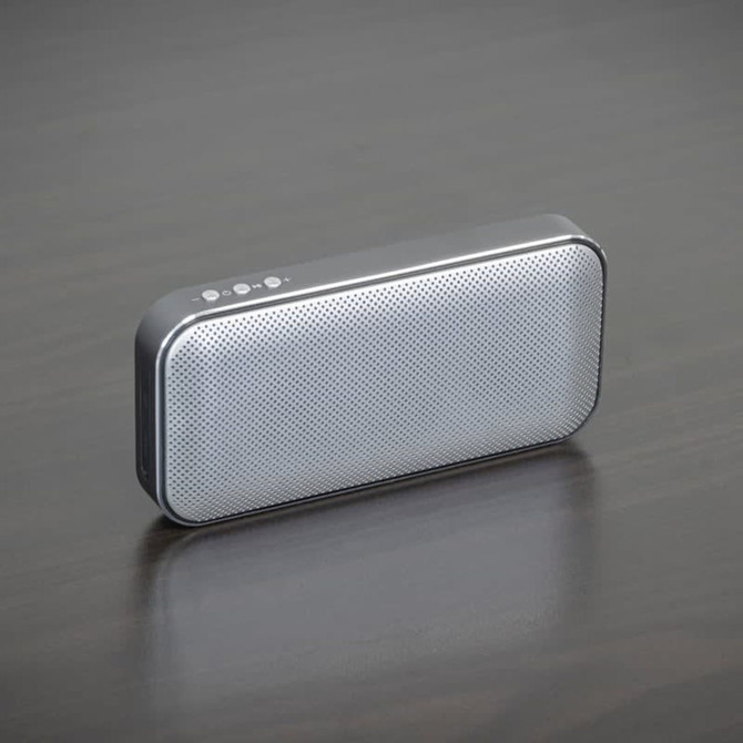 A grey Bluetooth speaker power bank with a sleek design and a textured surface, featuring a logo on the side.