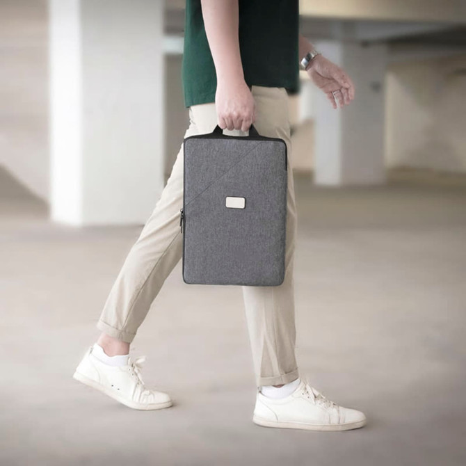 A person walking in a grey laptop sling bag, featuring a simple design and carrying handle.