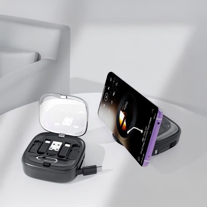 A black retractable cable set in a case, with a smartphone propped up, displaying a music player interface.