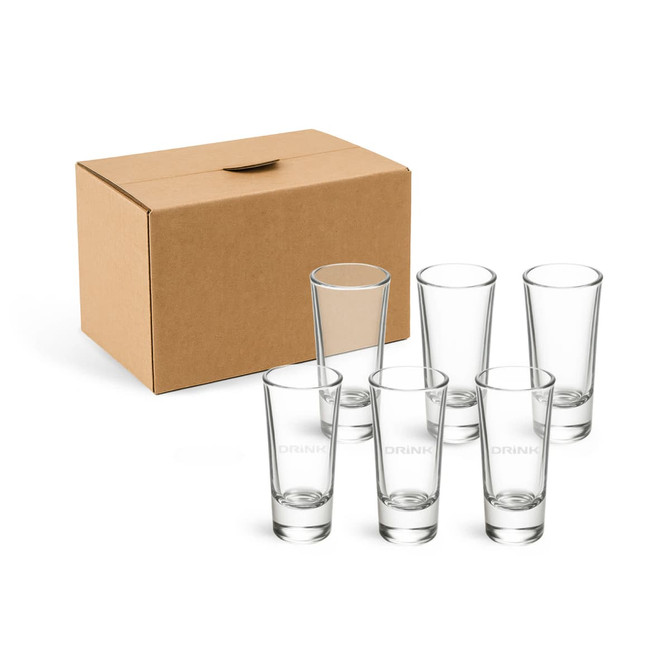 A set of six clear glass shot glasses beside a cardboard box. The glasses are tall and slender.