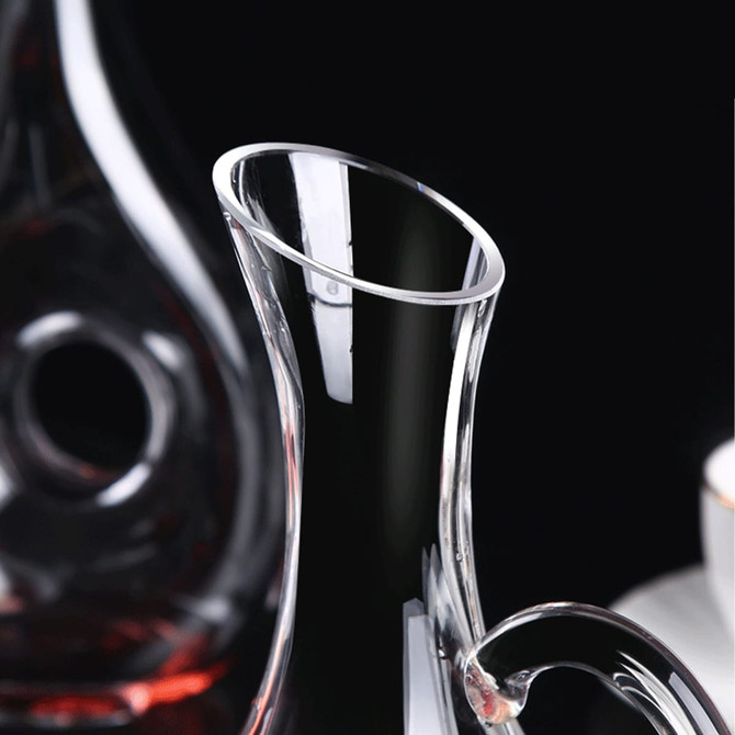 A handled wine decanter made of clear glass, featuring a sleek design and a distinctive pouring spout.
