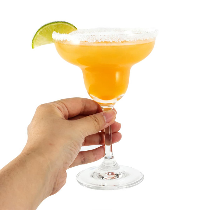A margarita glass filled with orange drink, garnished with a lime wedge and salt on the rim. Hand holding the glass.