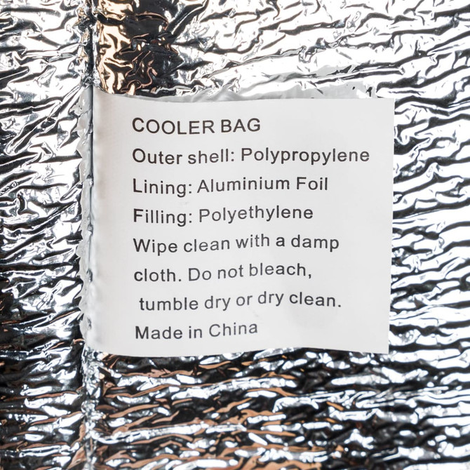 A silver cooler bag with a reflective exterior, featuring a label with care instructions and material information.