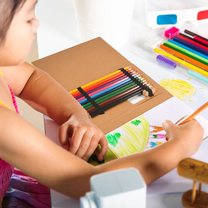A drawing set with various colored pencils displayed alongside a child drawing on white paper.