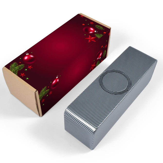 A silver speaker with a textured finish next to a decorative red box featuring holiday-themed graphics.