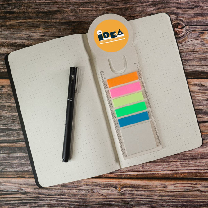 A Circle Milk Carton Bookmark in pastel colors with a ruler, placed on a dotted notebook alongside a black pen.