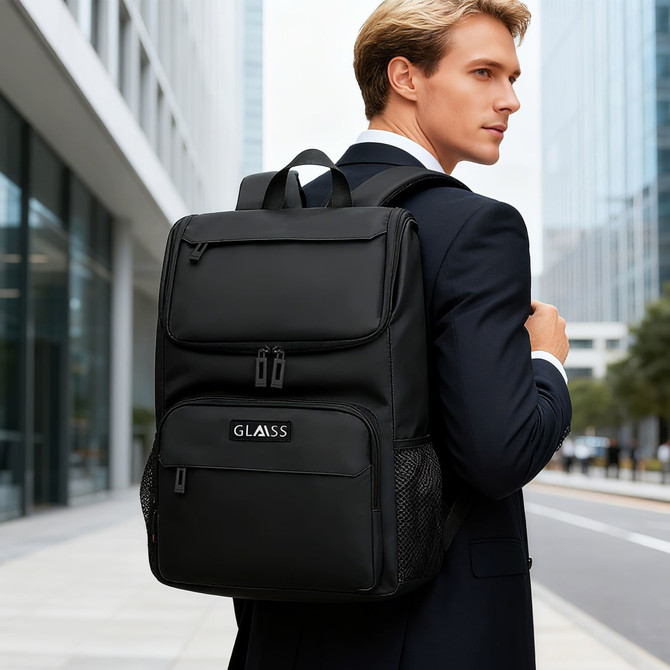 A black business laptop backpack with various compartments, carried by a man in a suit outside a modern building.