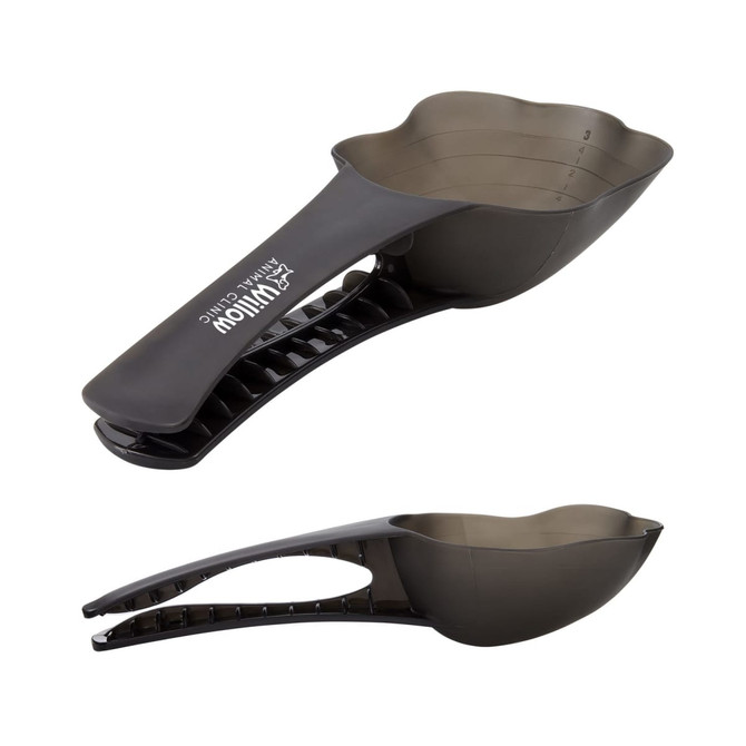 A pet food scoop in dark grey with a contoured handle and measuring markings on the scoop. It features a logo.