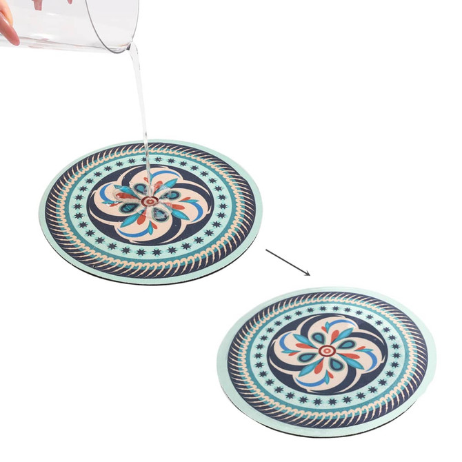A round, absorbent trivet features a floral design in blue, pink, and cream, with a contrasting black border.